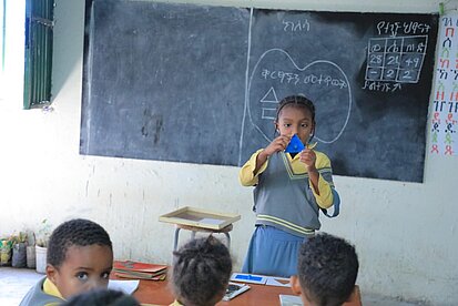 Ein Kind betrachtet im Matheunterricht die Schablone eines Dreieicks