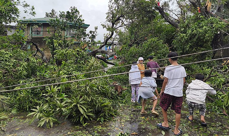 Kinder bahnen sich einen Weg durch umgestürzte Strommasten und abgerissene Äste