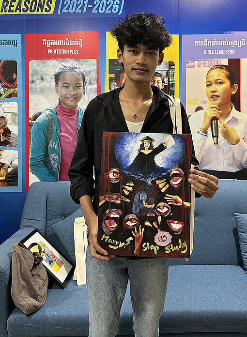 Ein junger kambodschanischer Mann hält ein Kunstwerk in der Hand