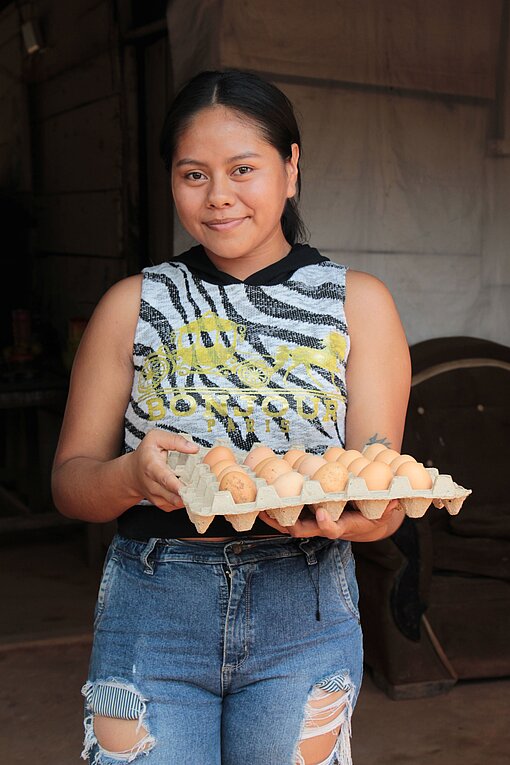 Eine junge Frau hält ein großes Packet Eier im Arm
