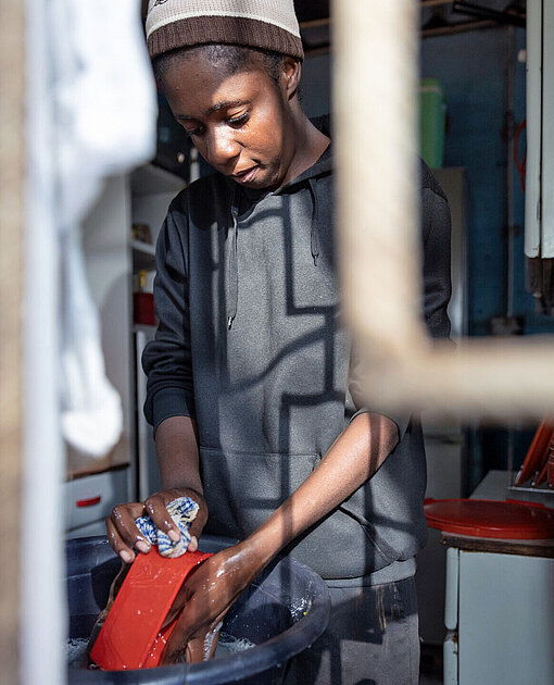 Eine junge Frau steht in einer Küche und wäscht ab