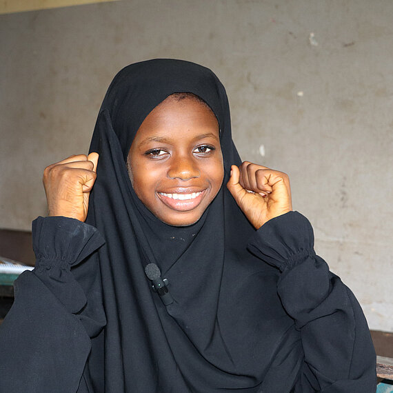 Ein Mädchen hebt lächelnd beide Fäuste