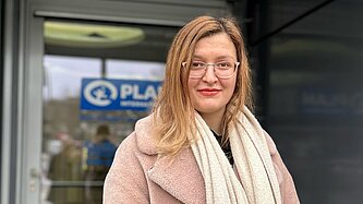 Oksana steht vor dem Pan-Gebäude und schaut in die Kamera