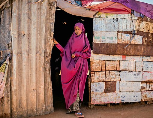 Barwaaqe (19) aus Somalia sagt, dass sie die Tortur der weiblichen Genitalverstümmelung (FGM) traumatisiert habe Eine junge Frau steht vor einer Hütte