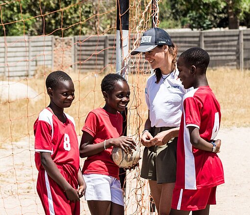 Drei Mädchen und eine Frau in Sportbekleidung stehen zusammen und besprechen sich