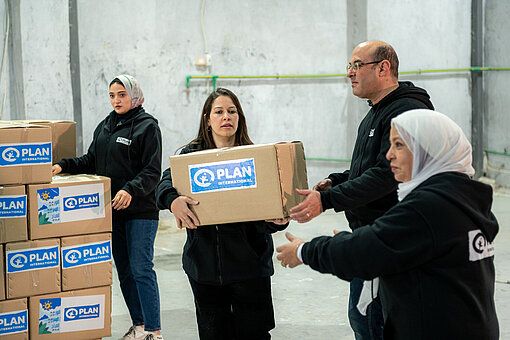 Ein Plan-Team in Ägypten bereitet Pakete mit Hilfsgütern für den Transport nach Gaza vor Frauen und Männer transportieren Plan-Pakete