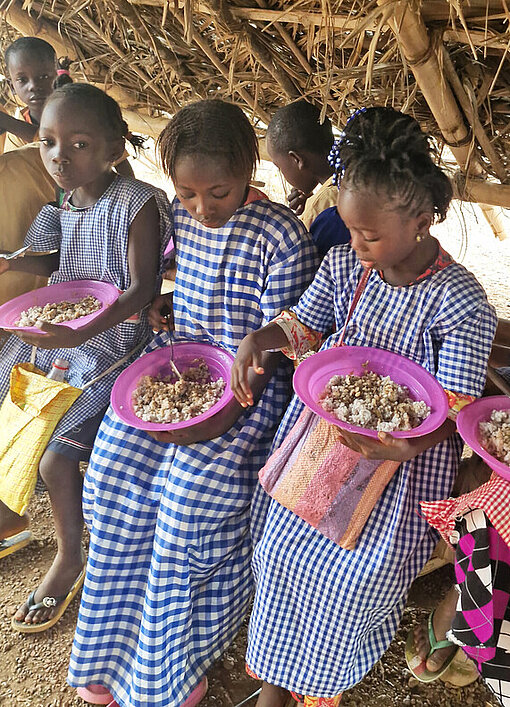 Mädchen aus Guinea essen das gemeinschaftlich organisierte Essen der Schule