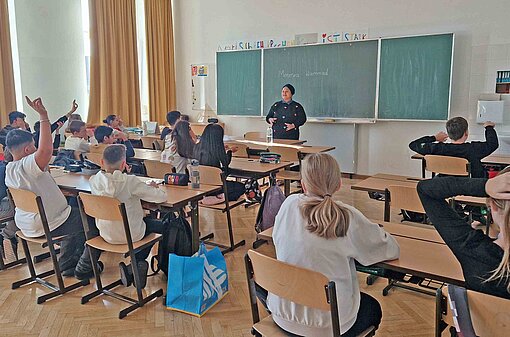 Plan-Botschafterin Menerva Hammad zeigt den Kindern, dass sie alle schreiben könne Ein Klassenraum mit Kindern, Lehrerin und Tafel