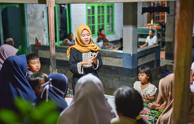 Eine junge Frau diskutiert mit Dorfbewohnerinnen