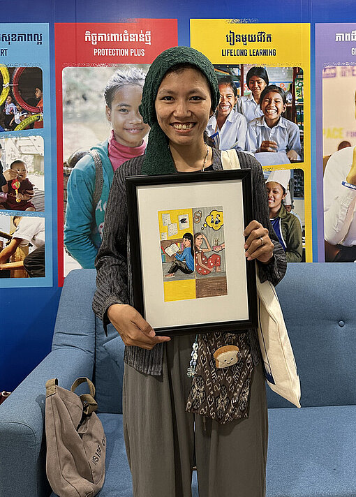 Eine junge kambodschanische Frau hält ein Kunstwerk in der Hand