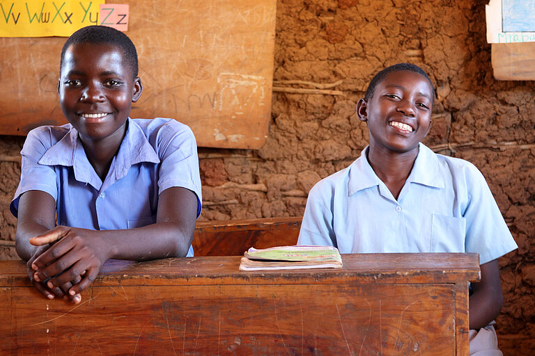 Zwei kenianische Mädchen sitzen an einem Schultisch