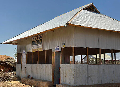 Ein Schulgebäude aus Holz mit Wellblechdach