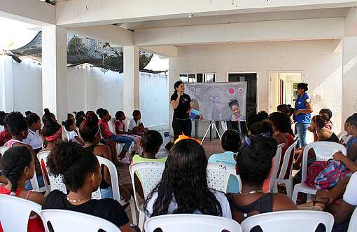 Workshop zum Thema Menstruation Viele Menschen sitzen in einem Raum, in dem ein Workshop stattfindet. Sie sind von hinten mit Blick auf die Vortragende fotografiert