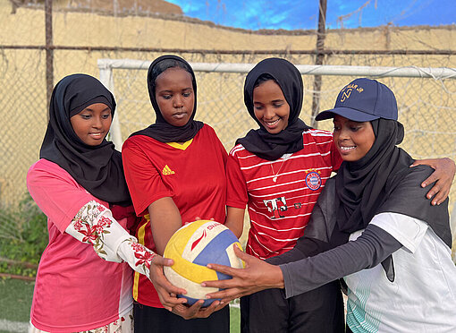 Eine Gruppe Mädchen hält einen Fußball in der Hand Eine Gruppe Mädchen hält stolz einen Fußball in der Hand