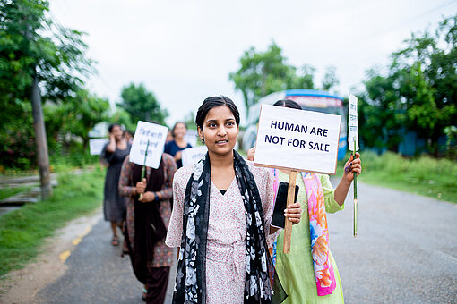 Engagement für Frauenrechte in Nepal Eine Gruppe Frauen mit Plakaten läuft über eine Straße, eine junge Frau geht mit ihrem Plakat voran