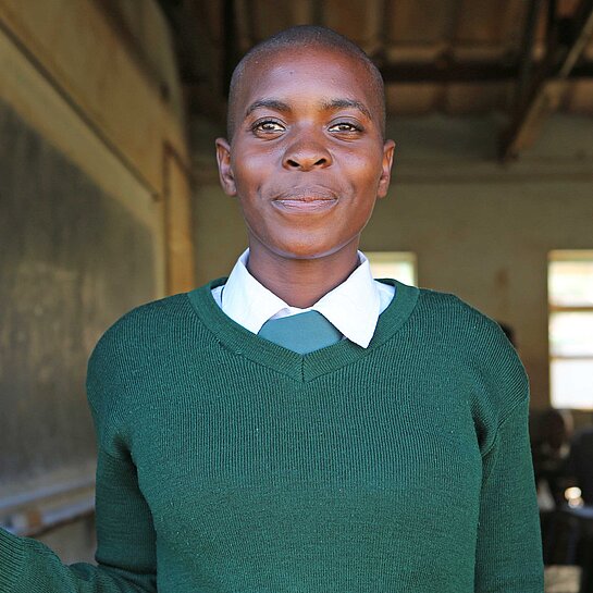 Ein Schulmädchen steht vor der Tür eines Klassenzimmers in Simbabwe