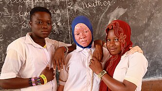 Rachidatou mit Klassenkameradinnen ihrer Schule stehen im Klassenraum 