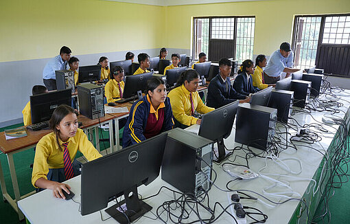 Kinder in Schuluniform sitzen vor Bildschirmen