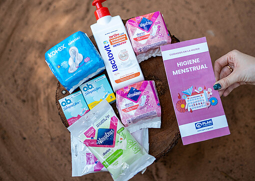Binden, Tampons, Reinigungstücher, Waschlotion und ein Flyer über Menstruationshygiene