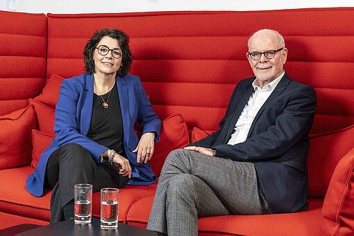 Frau und Mann sitzend auf rotem Sofa