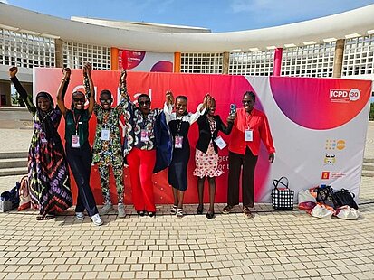 Frau stehen vor einem Banner und halten sich jubelnd an den Händen