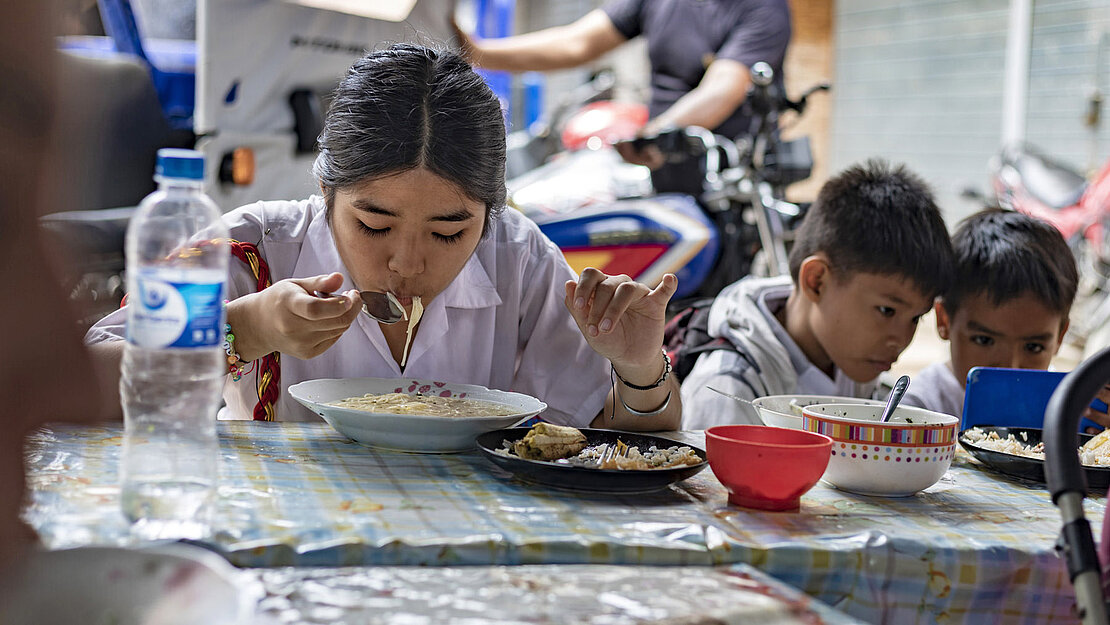 Nach der Schule geht Natsumi (16) für das Mittagessen zum Imbiss ihrer Mutter Ein Mädchen isst Nudeln
