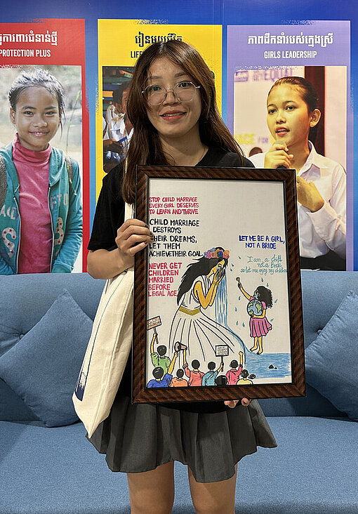 Eine junge kambodschanische Frau hält ein Gemälde in der Hand