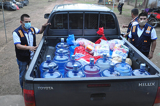 Plan Mitarbeiter:innen bei Hilfslieferungen an betroffene Familien in Bilwi, Nicaragua. Plan Mitarbeiter laden Kanister aus einem Truck.