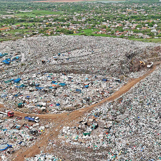 Eine Luftaufnahme zeigt Lastwagen, die vor einen großen Berg von Müll fahren