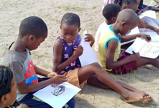 Kinder sitzen auf dem Boden und malen