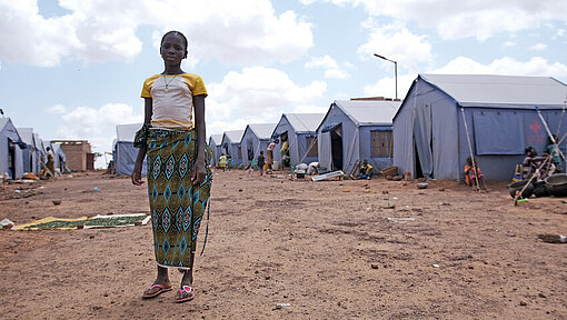 Mädchen steht zwischen Zelten in Vertriebenenlager 