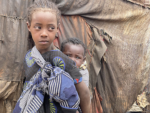 Warum hat Hunger Auswirkungen auf die Bildung von Kindern? Ein Mädchen trägt ein Baby auf dem Rücken