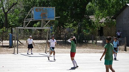 Auf dem neuen Sportplatz der Schule spielen Mädchen wie Jungen gerne Fußball.
