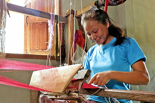 Eine Frau in Laos sitzt am Webstuhl
