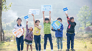 Kinder in Vietnam halten Schilder mit Botschaften zu Gleichberechtigung hoch Eine Gruppe von Kindern in Vietnam hält Schilder mit Botschaften wie "I'm helping girls get equal" und "Girl power". Sie stehen auf einer Wiese und zeigen ihre Unterstützung für Geschlechtergleichstellung.