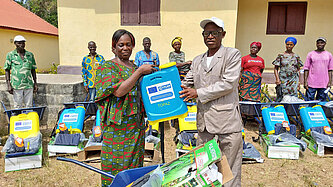 Eine Frau und ein Mann halten einen Kanister und Ausrüstung in den Händen.