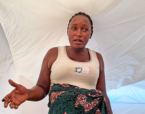 Eine Frau steht in einem Zelt und erzählt angeregt