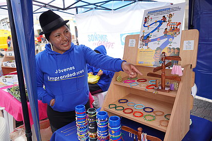 Ein Mädchen in Ecuador zeigt ihre selbstgemachten Armbänder, die sie auf dem Markt verkauft.