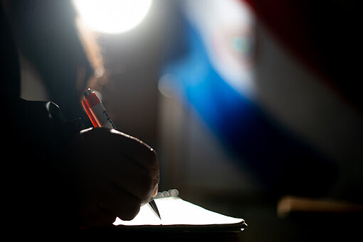 Eine Hand hält einen Stift und schreibt etwas auf Papier.