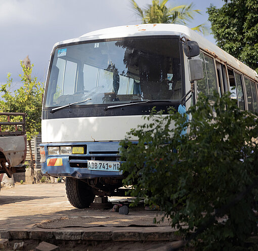 Ein kleiner Bus steht auf einem sandigen Parkplatz