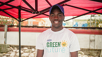 Ein junger Mann steht hinter einem Marktstand mit Schmuckgegenständen