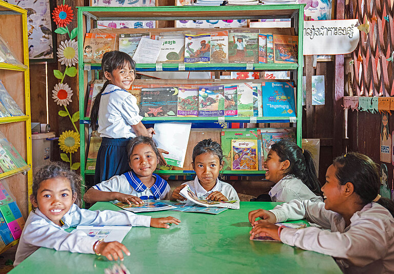 Kinder sitzen in einer Schulbibliothek