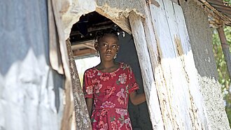 Ein kleines Mädchen steht in der Tür ihrer Hütte