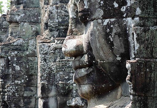 In eine massive Wand aus Sandsteinen ist ein riesiges lächelndes Gesicht geschlagen
