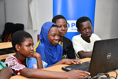 Vier Heranwachsende schauen gemeinsam auf einen Laptop