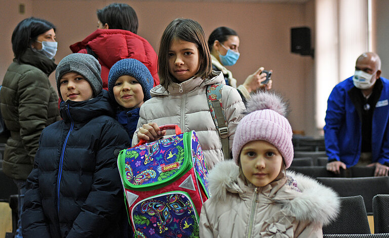 Eine gruppe Kinder posiert für die Kamera, ein Junge frech, einer cool, und zwei Mädchen lächeln mit einem neuen Schulranzen.