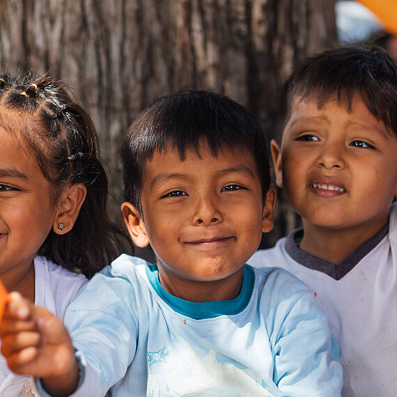 Drei kleine Kinder halten orange Luftballons