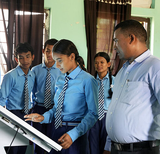 Kinder in Schuluniform bedienen einen großen Touchscreen