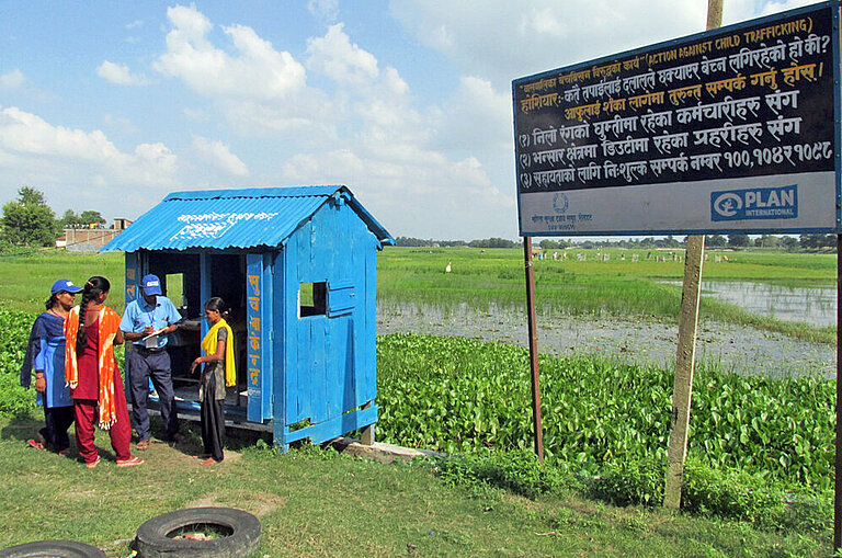 Plan-Teams an einem Kontrollposten an der Grenze zu Indien inmitten von Reisfeldern