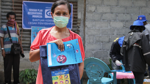 Eine Frau in Indonesien erhält ihr Hygienekit von Plan International.